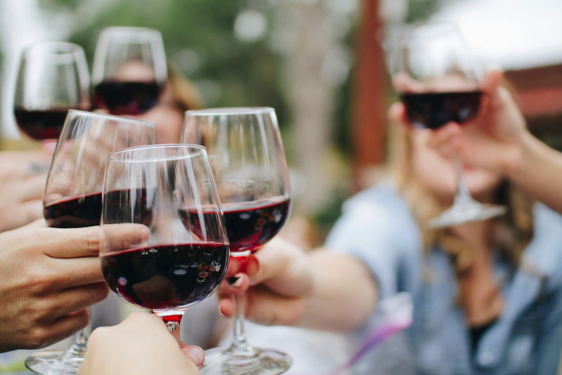 Verre de vin rouge servi à table avec une planche de fromages et charcuteries françaises